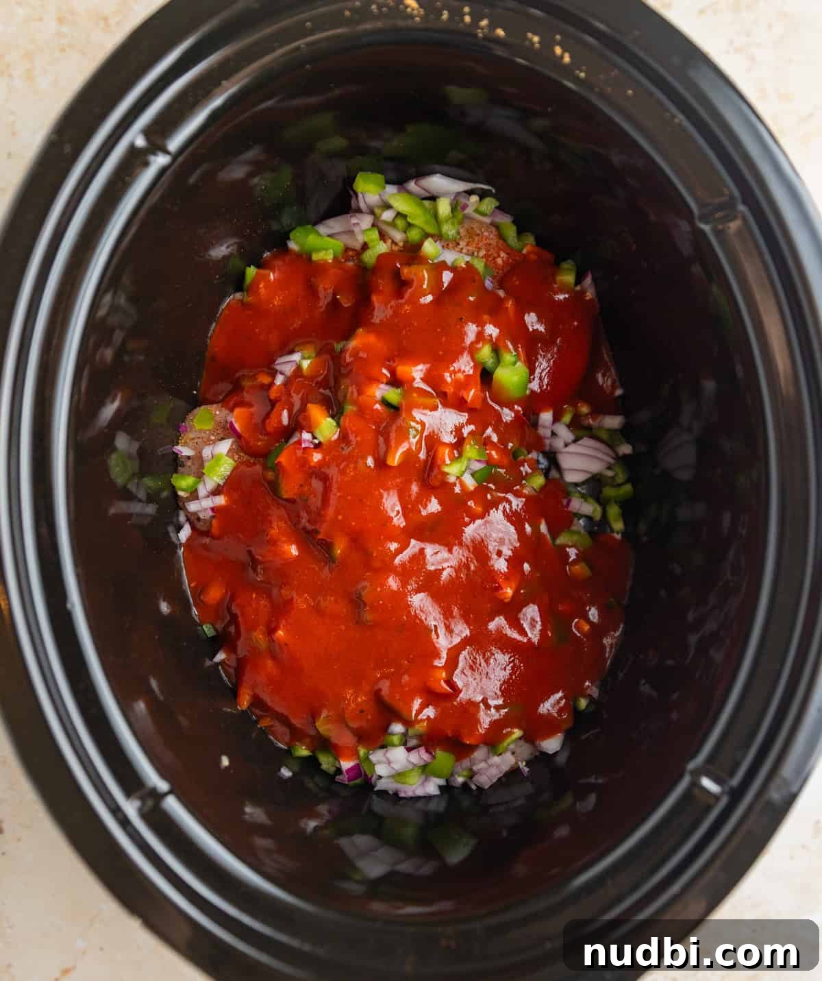 Slow Cooker BBQ Chicken Tacos with Crunchy Lime Slaw 4 Chopped pepper and onions over seasoned chicken breast topped with barbecue sauce in crockpot before cooking.