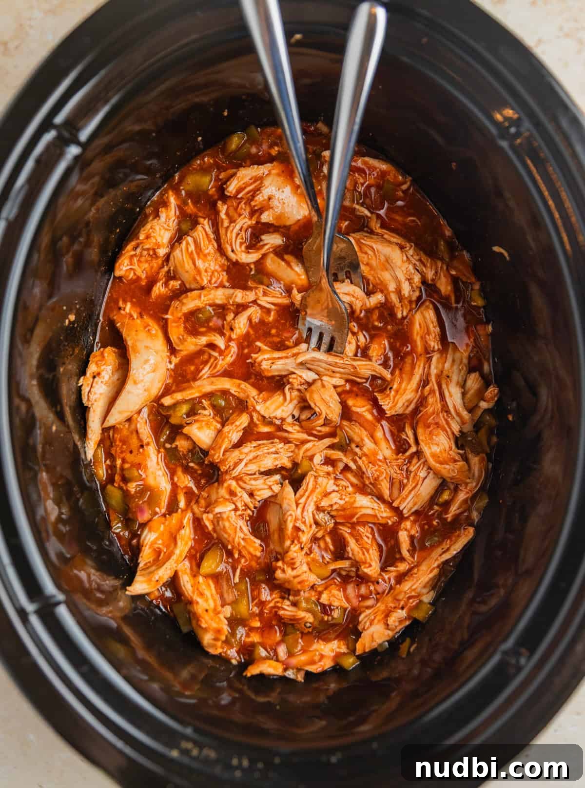 Slow Cooker BBQ Chicken Tacos with Crunchy Lime Slaw 6 Forks shredding bbq chicken breast in slow cooker pot.