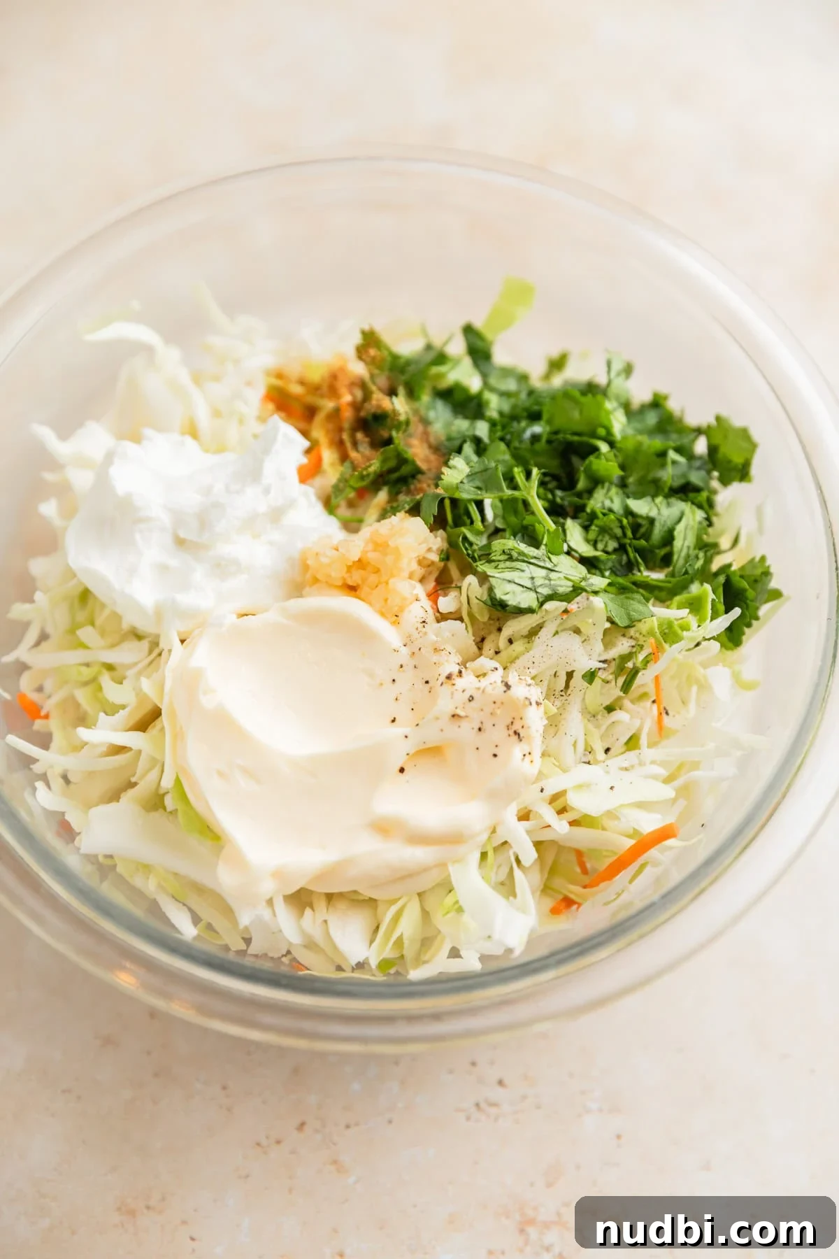 Slow Cooker BBQ Chicken Tacos with Crunchy Lime Slaw 7 Cabbage, mayo, sour cream, and other ingredients in glass mixing bowl.