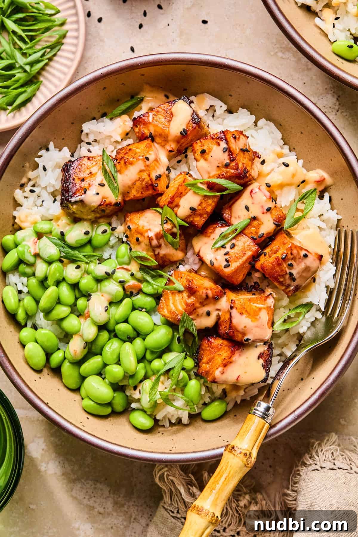 Crispy Air Fryer Salmon Bites with Lemon Garlic Dip 2 Dish with air fryer salmon bites topped with bang bang sauce and black sesame seeds.