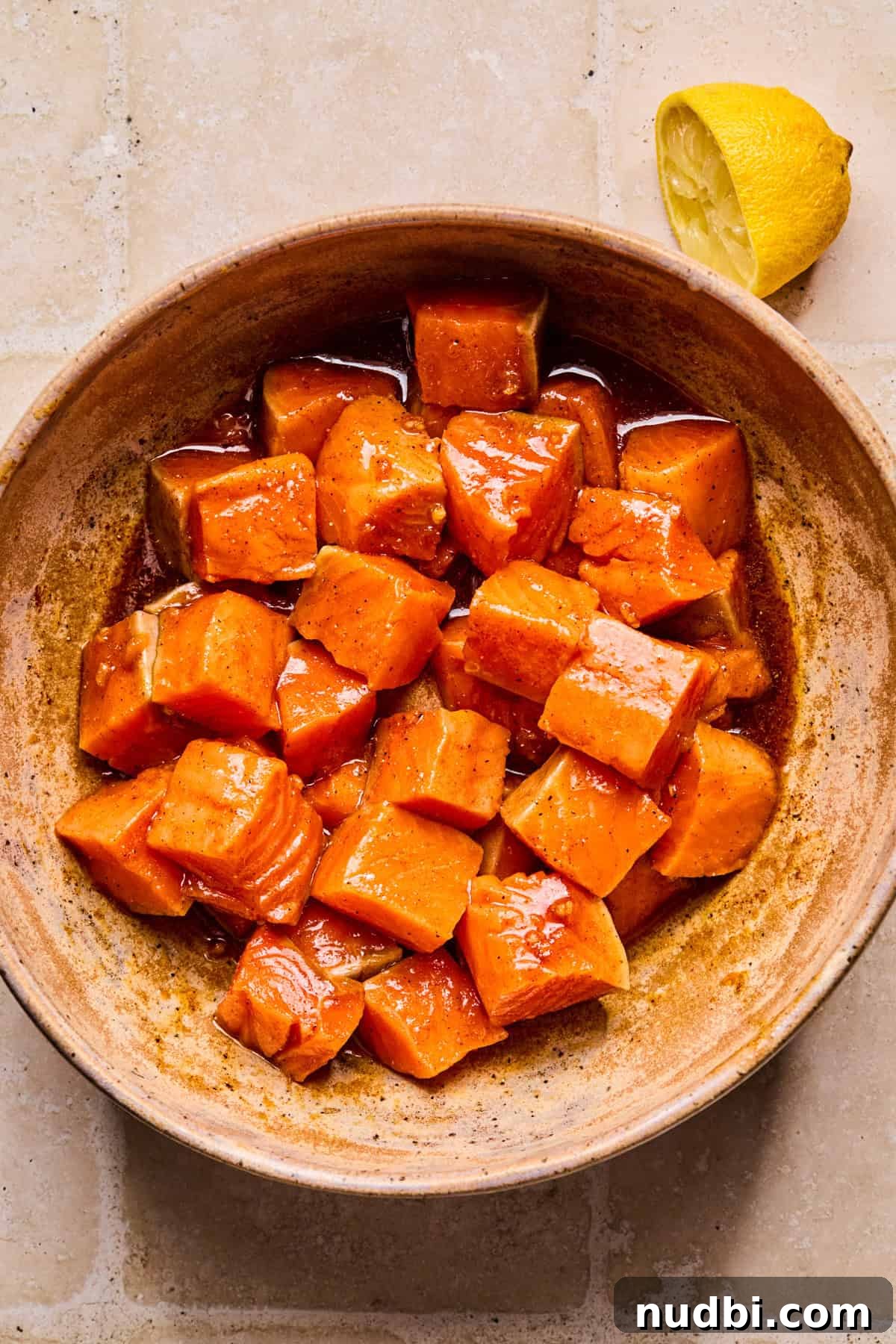 Crispy Air Fryer Salmon Bites with Lemon Garlic Dip 5 Salmon cubes in bowl with marinade.