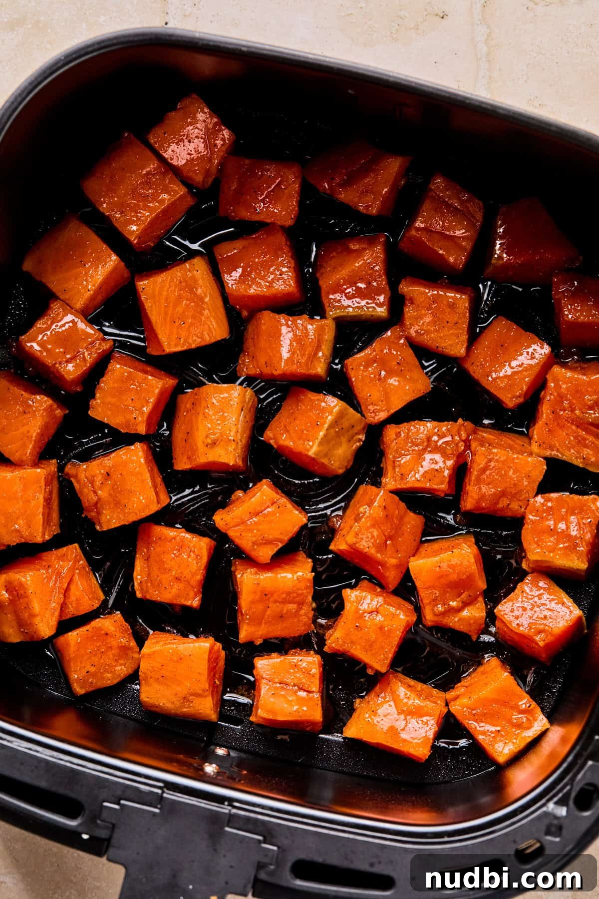 Crispy Air Fryer Salmon Bites with Lemon Garlic Dip 6 Raw salmon bites in air fryer basket before cooking.