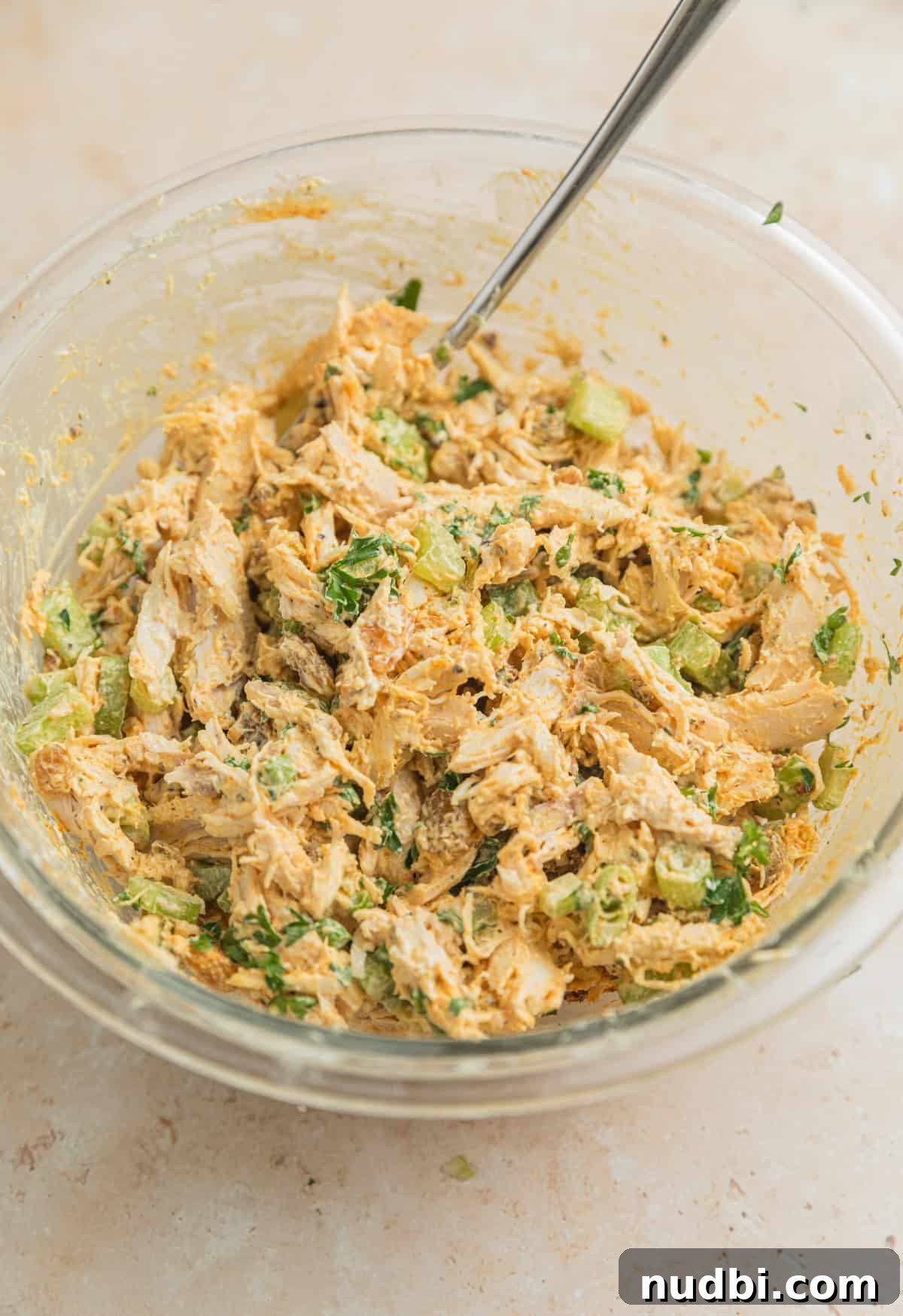 Creamy Curry Chicken Salad Recipe for Lunch or Light Dinner 5 Mixed curry chicken salad in glass mixing bowl with spoon.