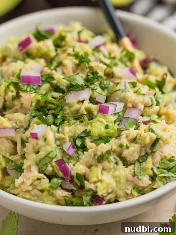 Cucumber and Sweet Corn Salad with Herb Vinaigrette 12 Bowl with spoon scooping into avocado tuna salad in bowl.