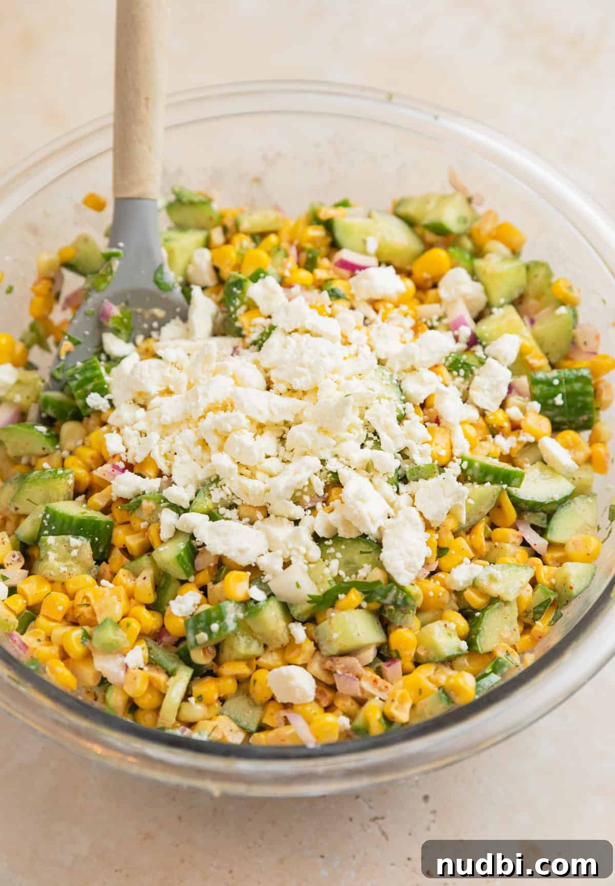 Cucumber and Sweet Corn Salad with Herb Vinaigrette 6 Tossed cucumber corn salad in bowl with feta cheese added on top before mixing.
