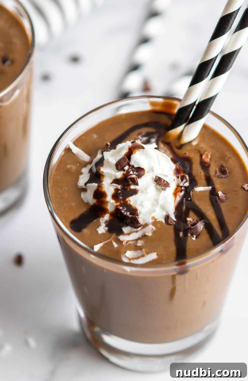 Chocolate Coconut Smoothie Recipe for Creamy, Decadent Flavor 2 Almond Joy Smoothie in glass with straws, cacao nibs, whipped cream.