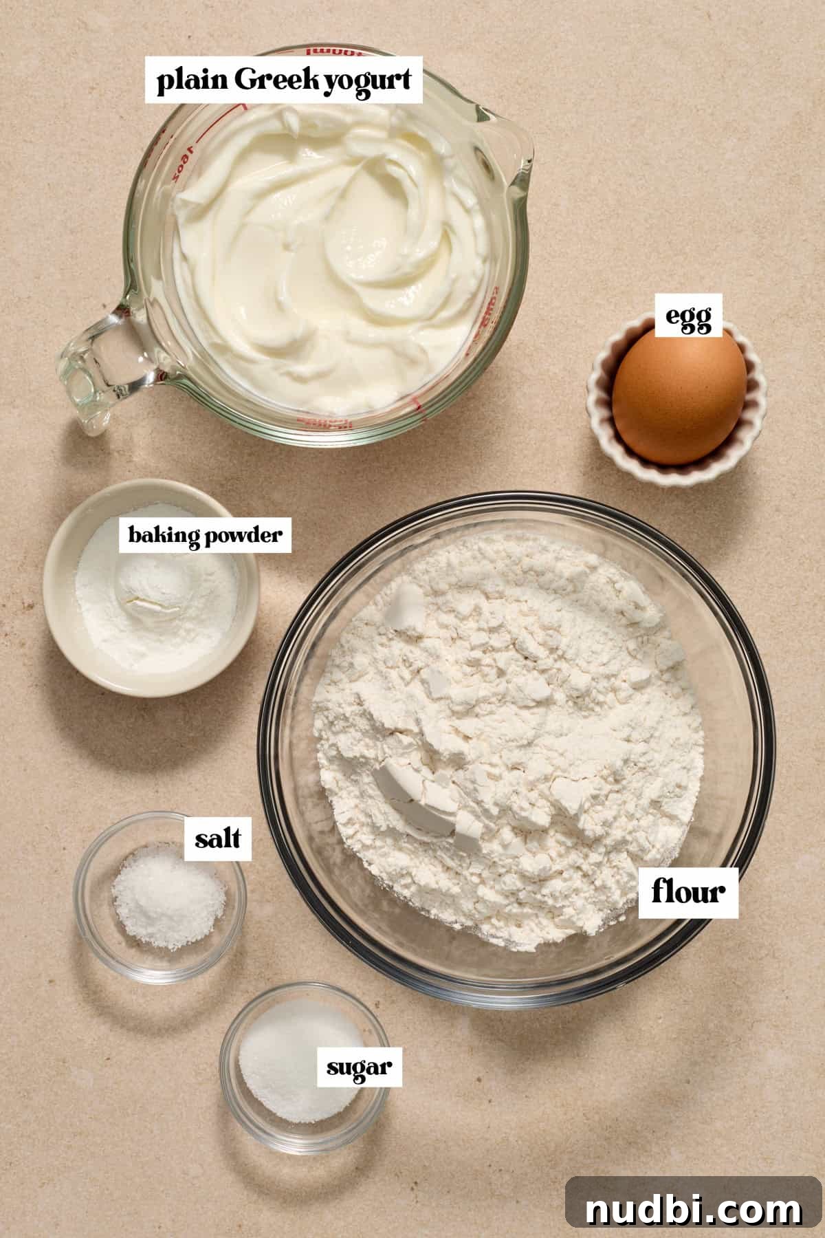 High-Protein Greek Yogurt Bagel Recipe 3 Flour, plain greek yogurt, egg and other ingredients to make recipe on surface.