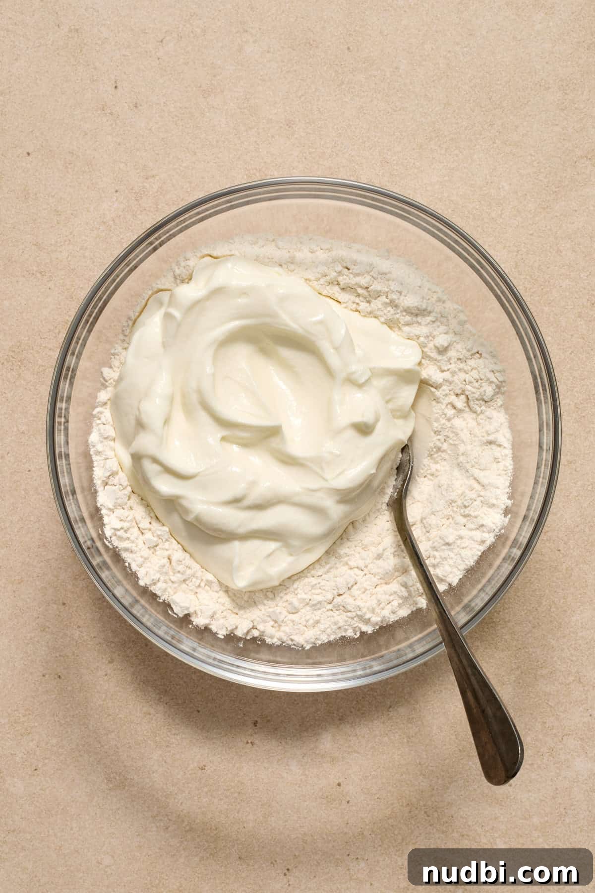 High-Protein Greek Yogurt Bagel Recipe 5 Greek yogurt added to bowl with flour and spoon.