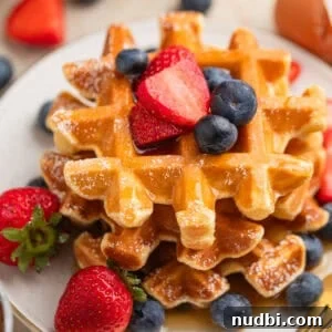 Cottage cheese waffles stacked on plate with berries.