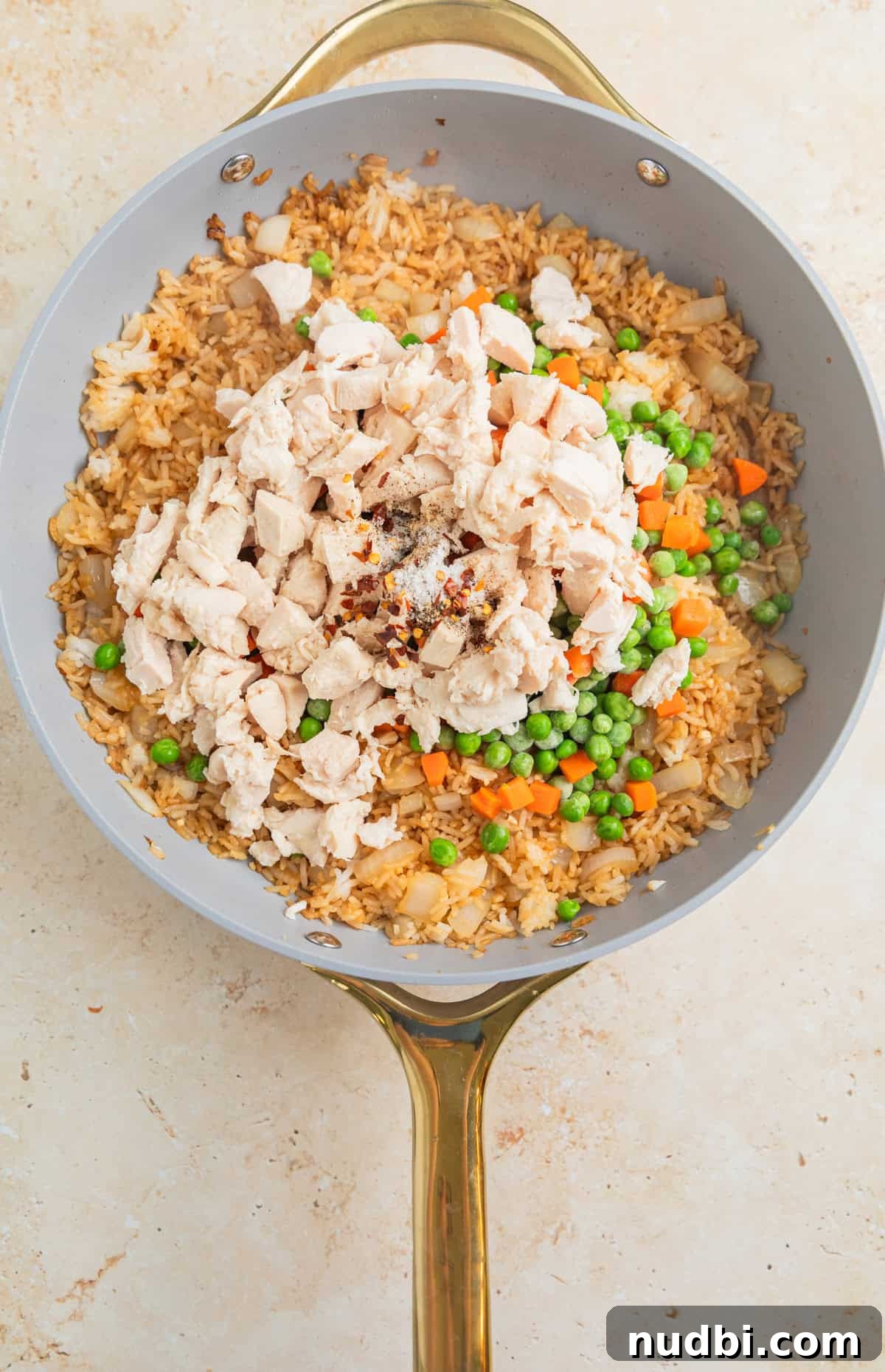 Quick Chicken Fried Rice Recipe for Perfect Weeknight Meals 7 Chicken, frozen peas and carrots and other ingredients added to skillet with fried rice.