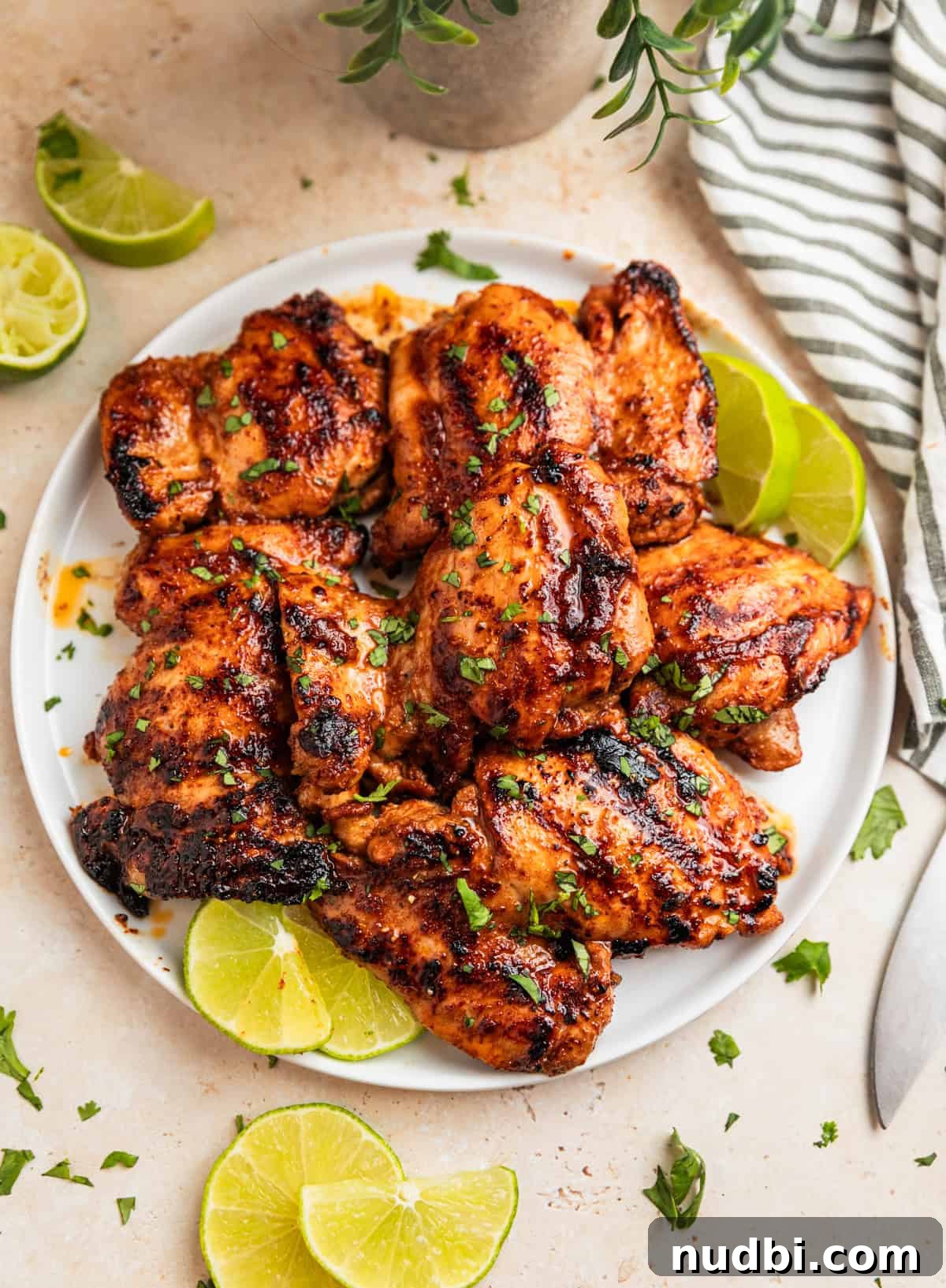Zesty Chili Lime Chicken Recipe for Tender Grilled Chicken 8 Grilled chicken thighs on white plate with sliced limes.