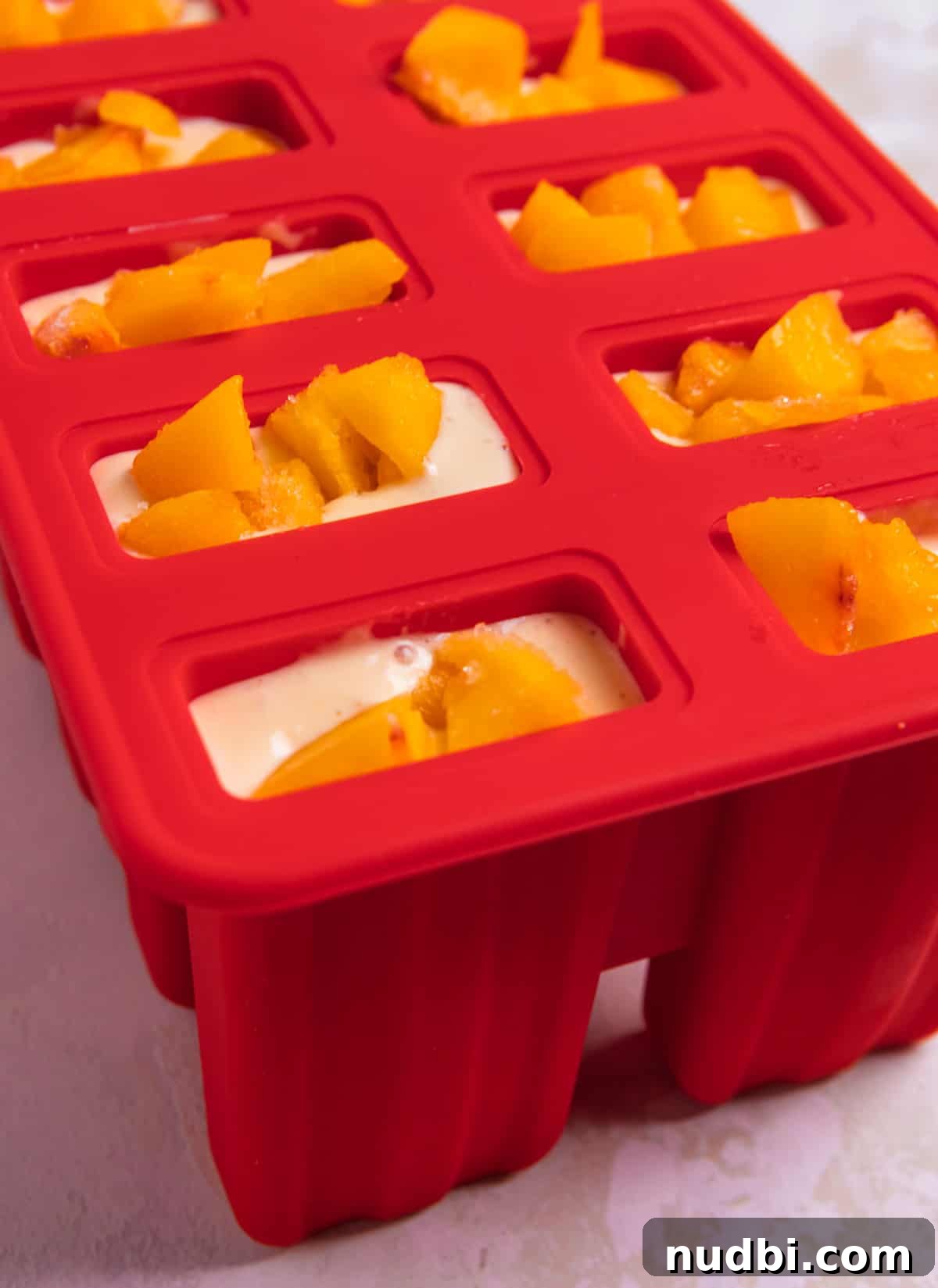 Popsicle molds filled with mixture and topped with peaches.