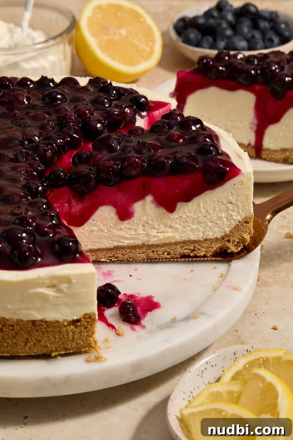 No-Bake Lemon Blueberry Cheesecake Recipe — Light & Creamy Dessert 9 Slice of lemon blueberry no bake cheesecake being pulled on spatula.