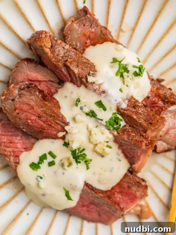 Sliced grilled ribeye steak sliced and served on plate with gorgonzola sauce.