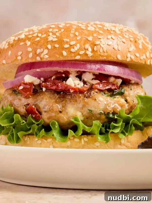 Turkey burger with spinach and feta on bun with lettuce, onion and other ingredients.