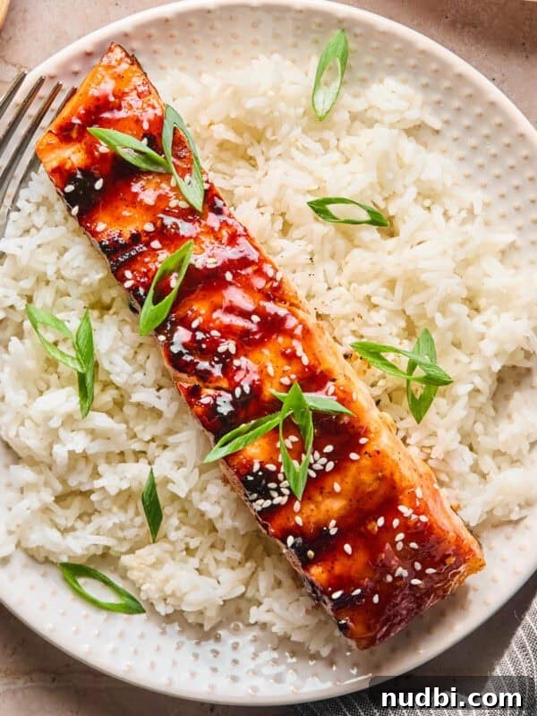 Grilled teriyaki salmon filet over rice with scallions and sesame seeds.