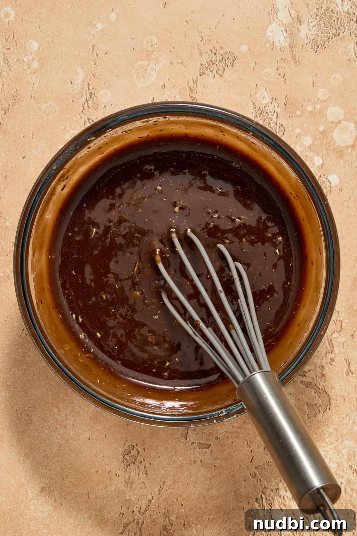 Balsamic marinade in glass bowl with whisk.