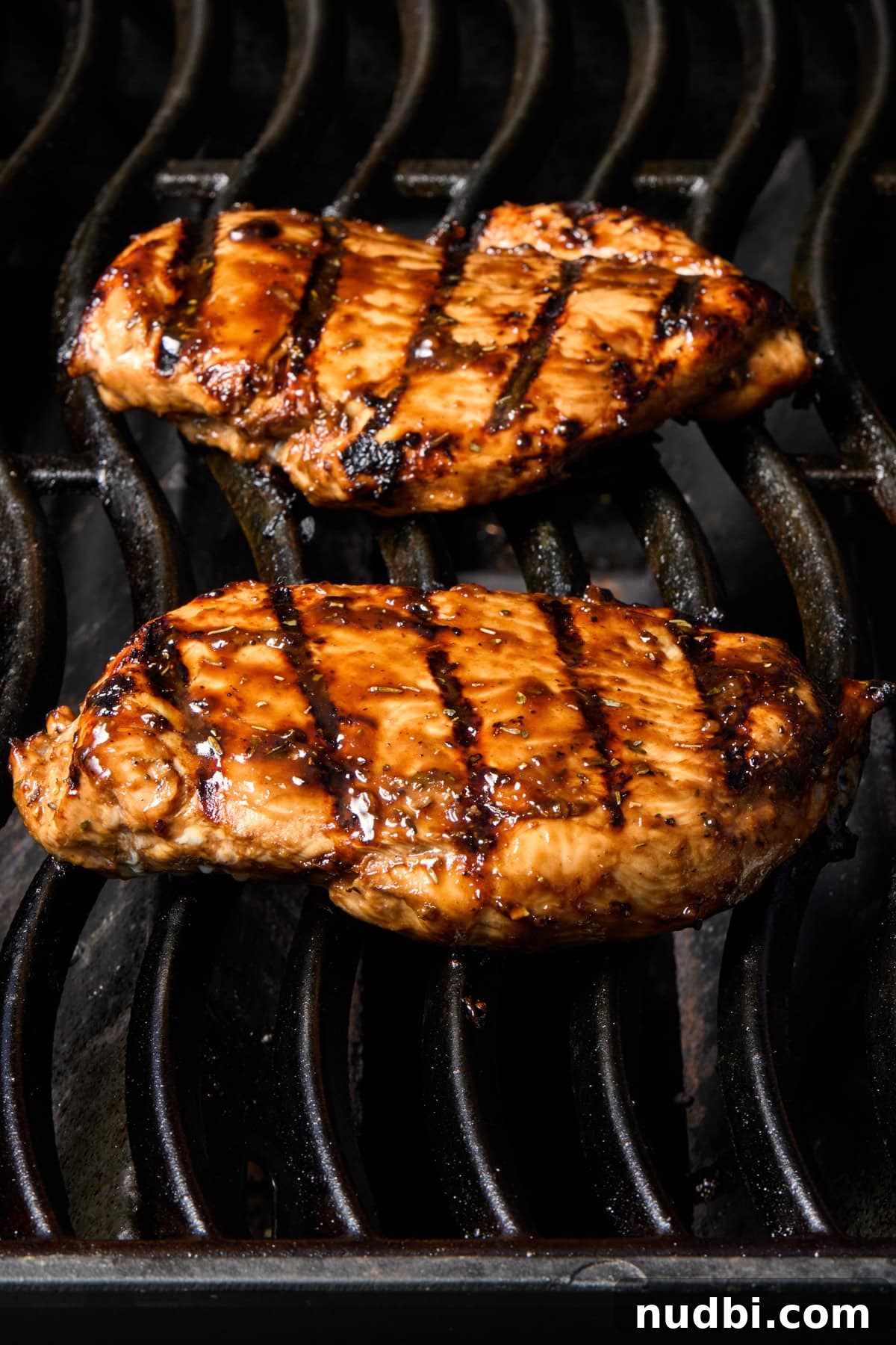 Chicken on grill with marinade brushed over top.