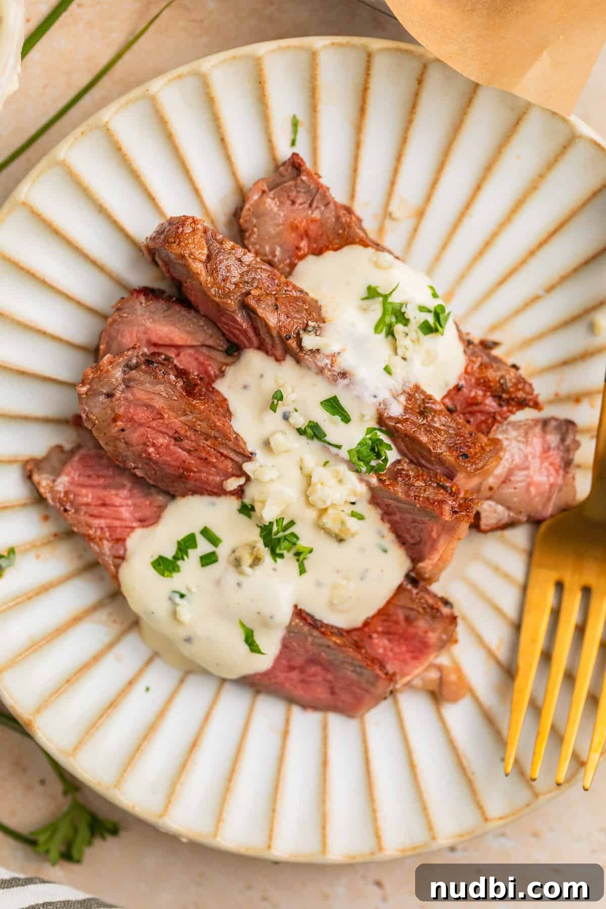 Grilled Ribeye with Creamy Gorgonzola Sauce Recipe 2 Sliced grilled ribeye steak sliced and served on plate with cheese sauce.