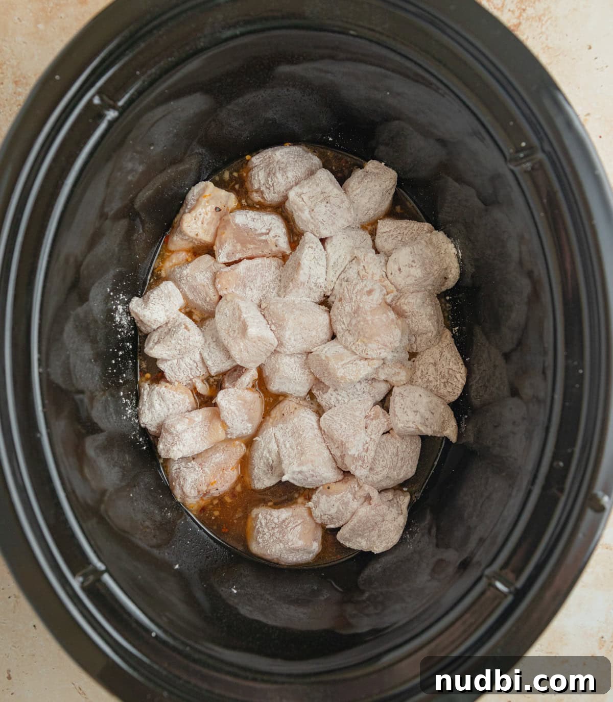 Slow-Cooker Orange Chicken Recipe for Tender, Saucy Chicken 7 Slow cooker pot with cornstarch coated chicken.