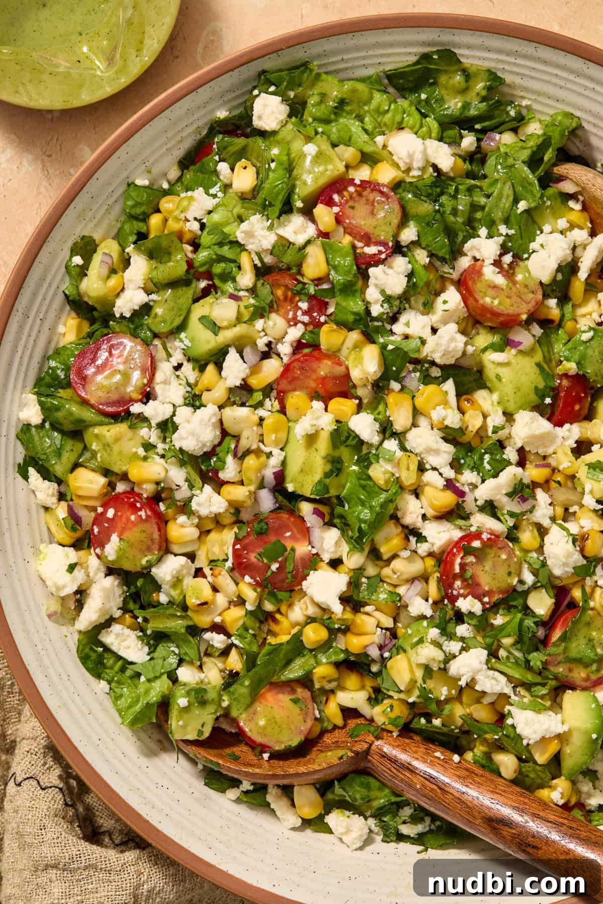 Grilled Corn Chopped Salad with Lime and Cotija 2 Grilled corn and tomato salad in bowl with wood spoon.