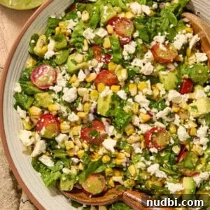 Grilled Corn Chopped Salad with Lime and Cotija 15 Salad with grilled corn, romaine, avocado, tomato in bowl.