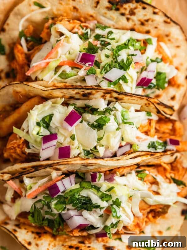 Slow-Cooker Shredded Beef Tacos Recipe for Tender, Flavorful Meat 13 BBQ chicken tacos topped with slaw and chopped cilantro and red onion on parchment.