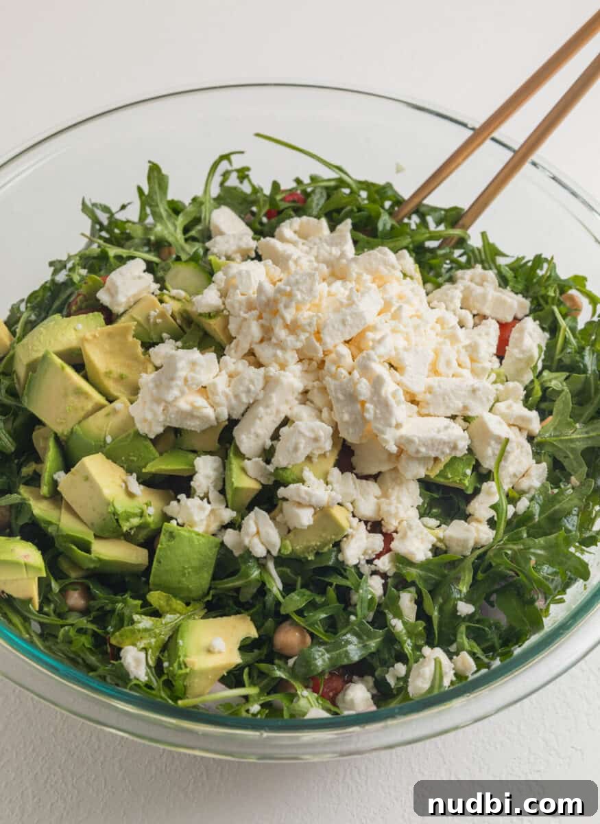Creamy Chickpea and Avocado Salad with Lemon Dressing 6 Feta cheese and diced avocado laying on top of salad ingredients in bowl before mixing.