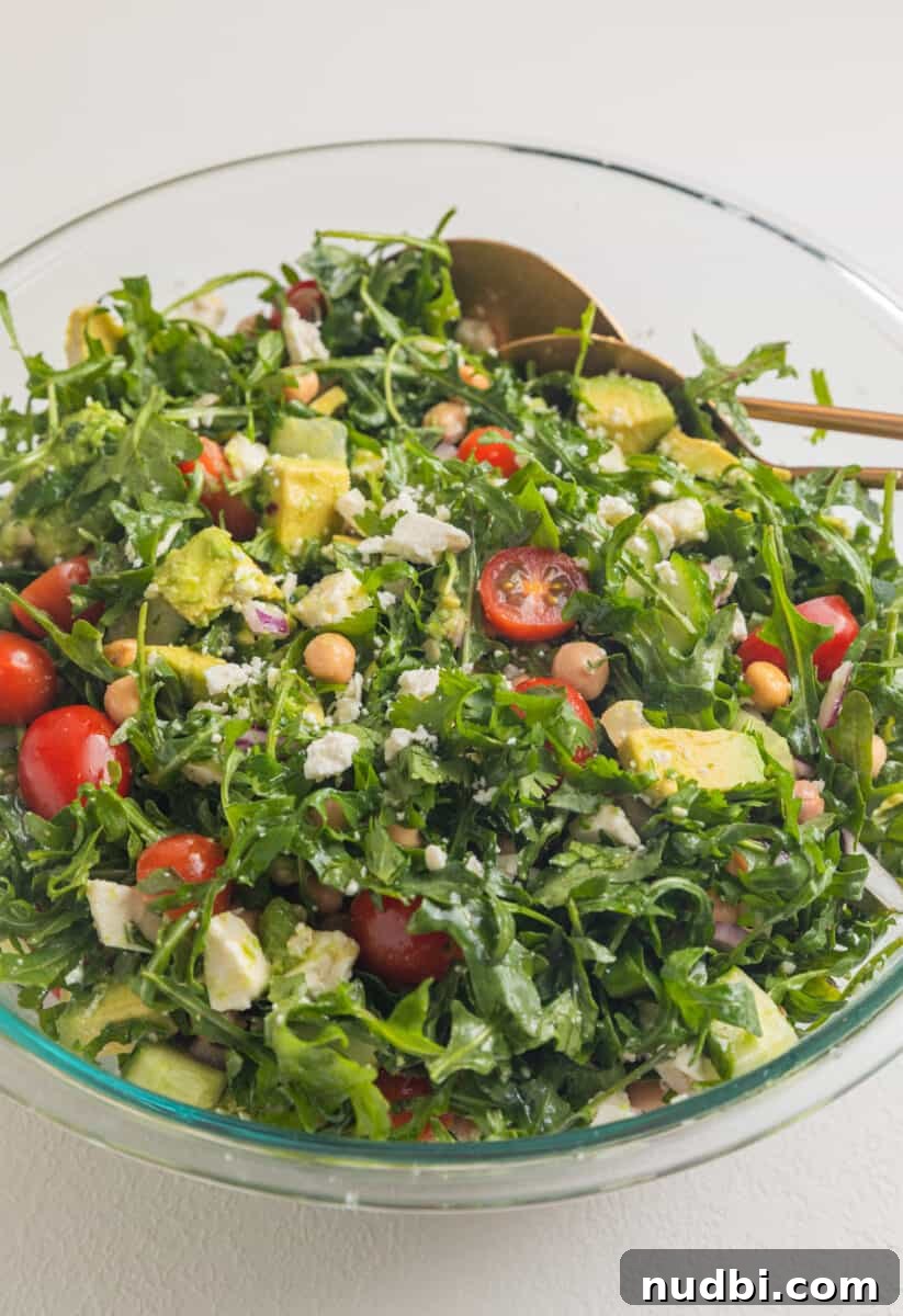 Creamy Chickpea and Avocado Salad with Lemon Dressing 7 Tossed arugula, chickpea and avocado salad with salad utensils.