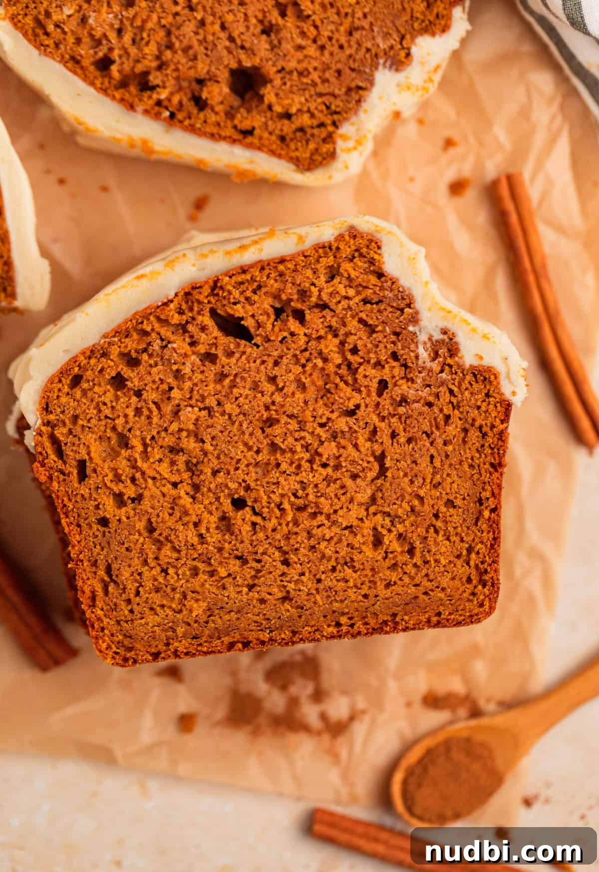 Pumpkin Bread Made from Cake Mix: Quick Moist Recipe 2 Slice of cake mix pumpkin bread with cream cheese frosting on parchment.