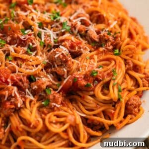 One-Pot Instant Pot Spaghetti Recipe for Quick Weeknight Dinners 11 Plate with spaghetti tossed in meat sauce with parmesan and herbs over top.