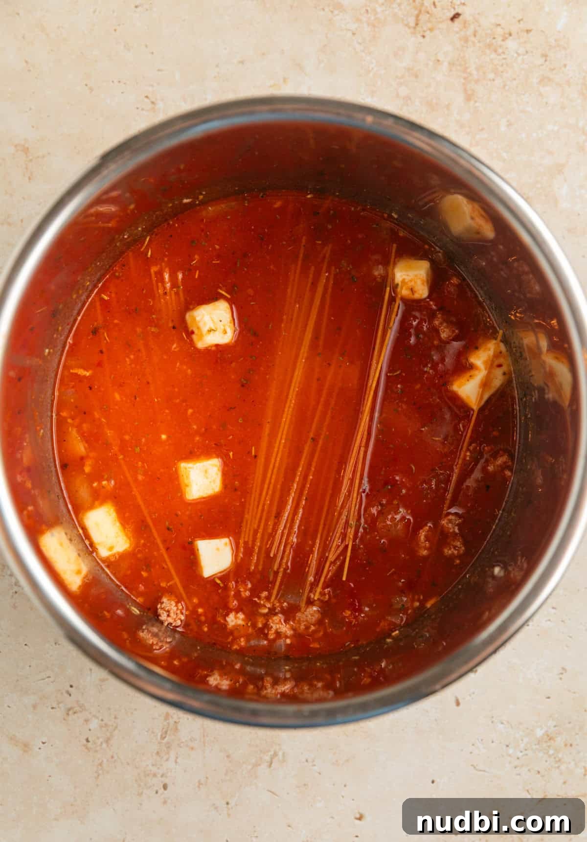 One-Pot Instant Pot Spaghetti Recipe for Quick Weeknight Dinners 7 Pasta, cubed butter, marinara sauce and broth added to Instant pot with browned meat.
