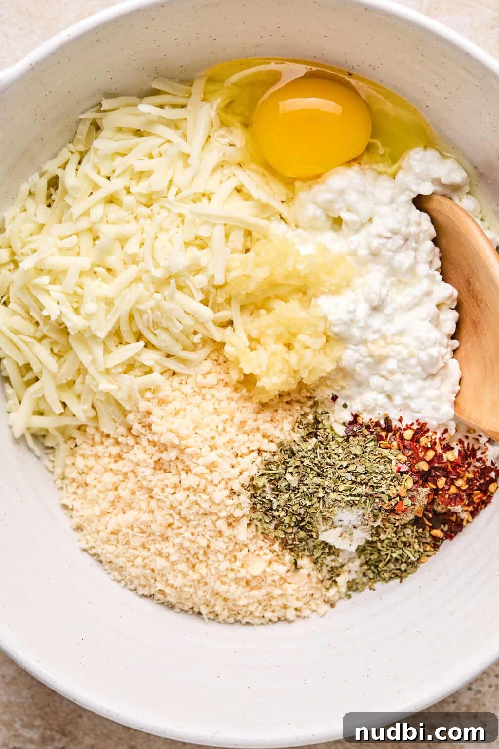 Spinach Baked Pasta with Creamy Cheese and Garlic 5 Cottage cheese, parmesan egg and other ingredients in mixing bowl with wooden spoon.