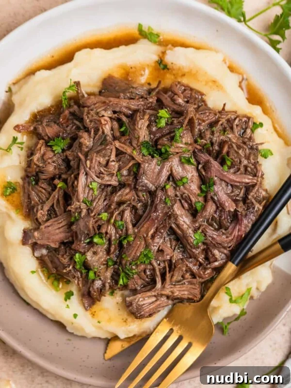 Slow Cooker Apricot-Glazed Chicken Recipe 14 Tan and white plate with crock pot shredded beef over mashed potatoes.