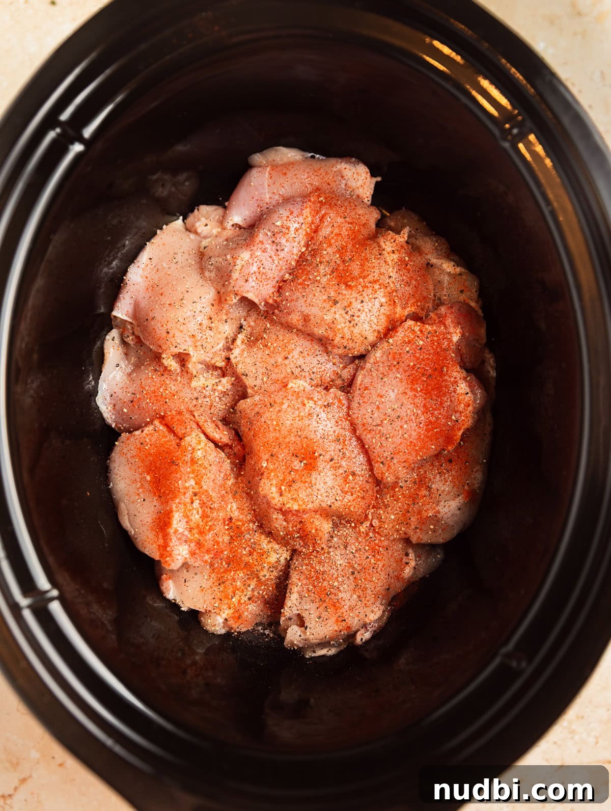 Slow Cooker Apricot-Glazed Chicken Recipe 4 Chicken thighs in crockpot with seasoning on top.