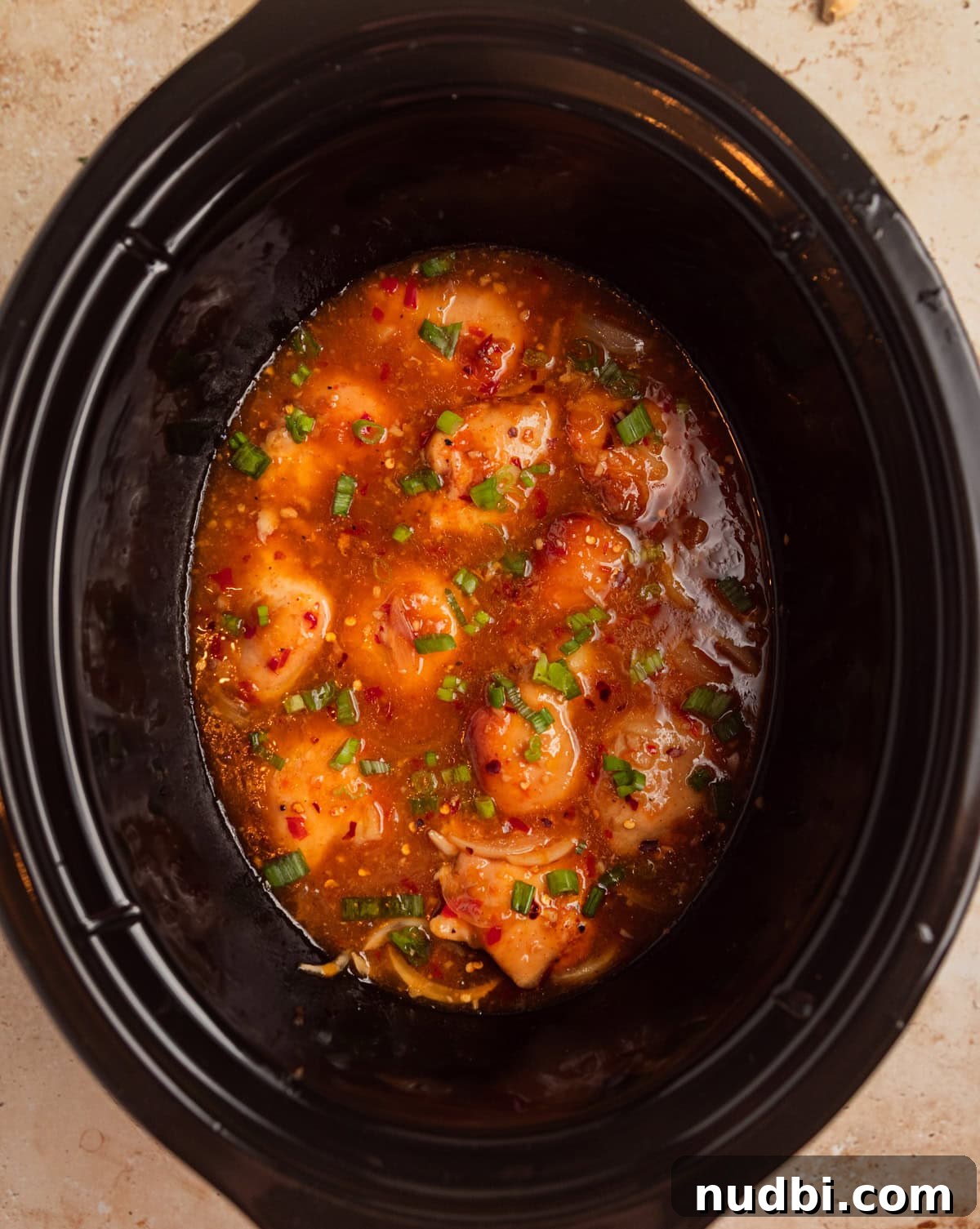 Slow Cooker Apricot-Glazed Chicken Recipe 9 Slow cooker apricot chicken in pot topped with sliced green onions on top.