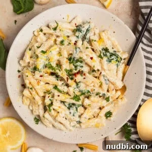 Plate with creamy pasta topped with chopped parsley and lemon zest.