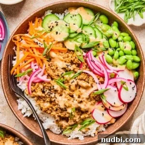 Rice bowl with ground turkey, bang bang sauce, cucumber, carrots and other ingredients.