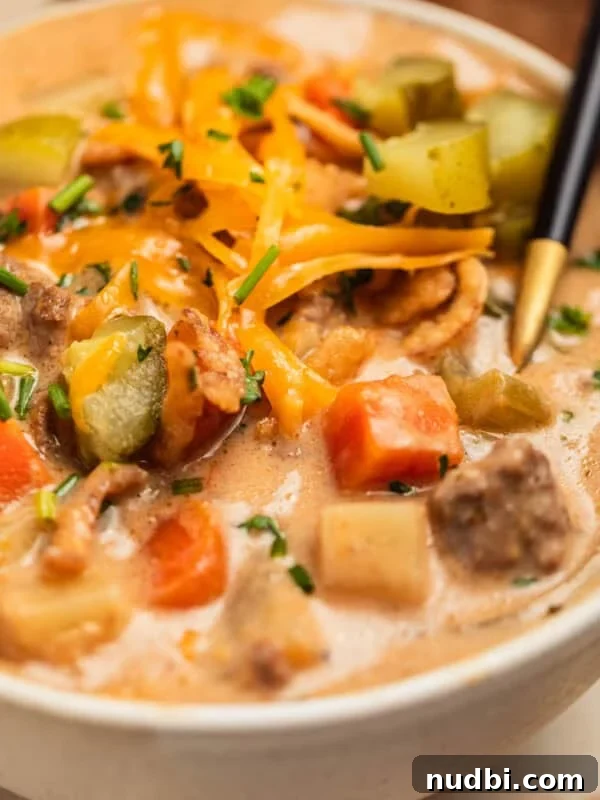 Crockpot cheeseburger soup served in bowl topped with cheese, pickles and parsley.