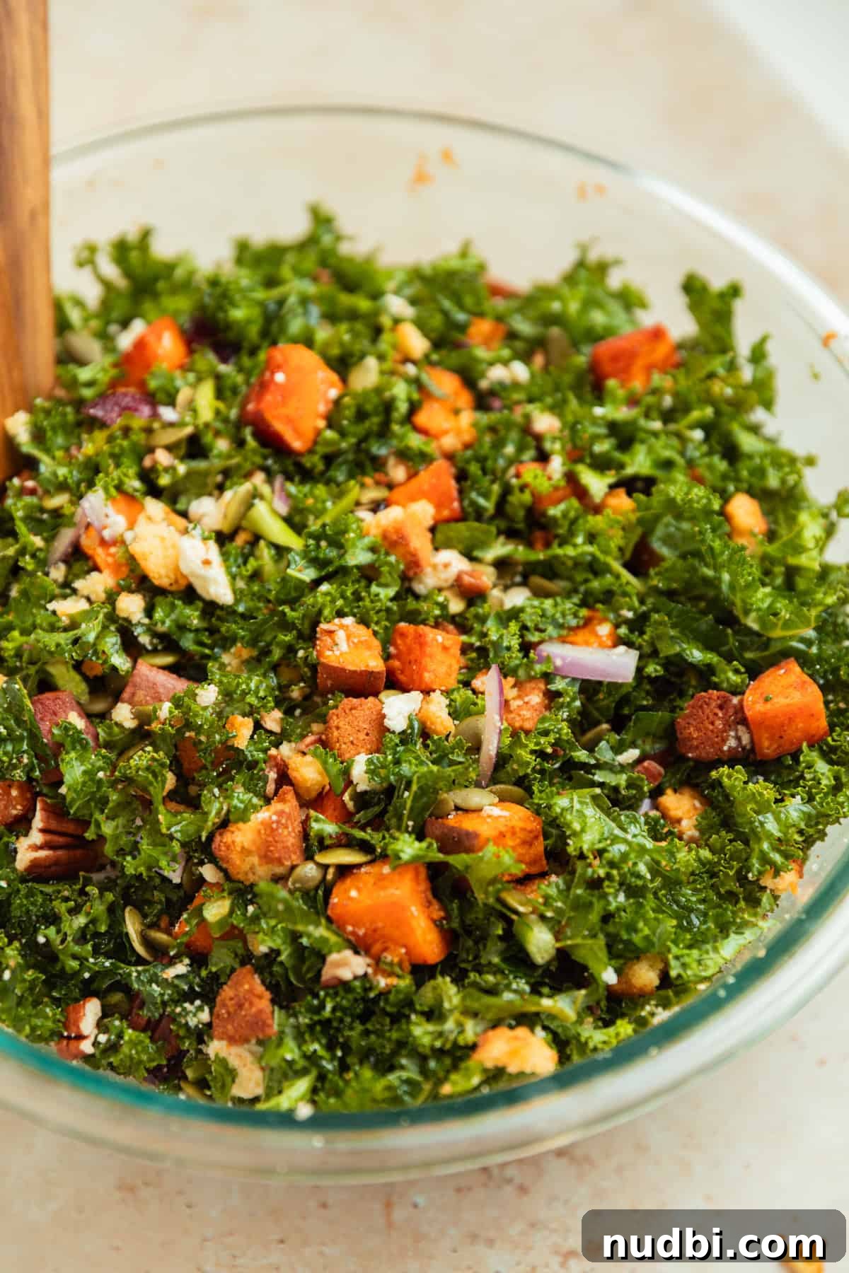 Roasted Sweet Potato and Kale Salad with Maple Dijon Dressing 11 Tossed sweet potato kale salad in glass bowl with tongs.