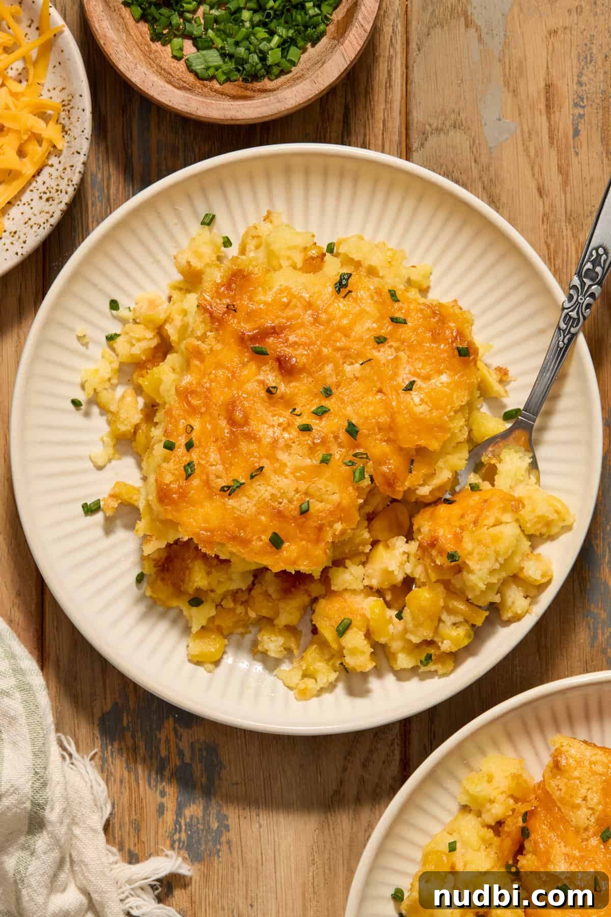 Cheesy cornbread casserole served on plate with chopped chives.