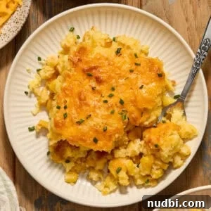 Cheesy Cornbread Casserole Recipe for Comforting Weeknight Dinner 18 Cheesy cornbread casserole on white dish with fork scooping in.
