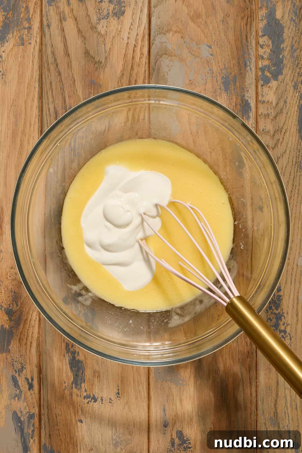 Sour cream added to bowl with egg and melted butter mixture.