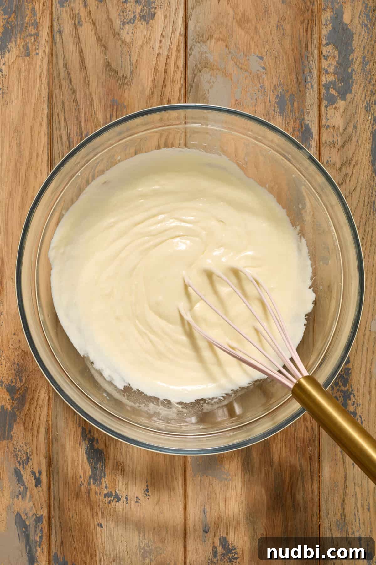 Sour cream, egg and butter mixed in bowl with whisk.