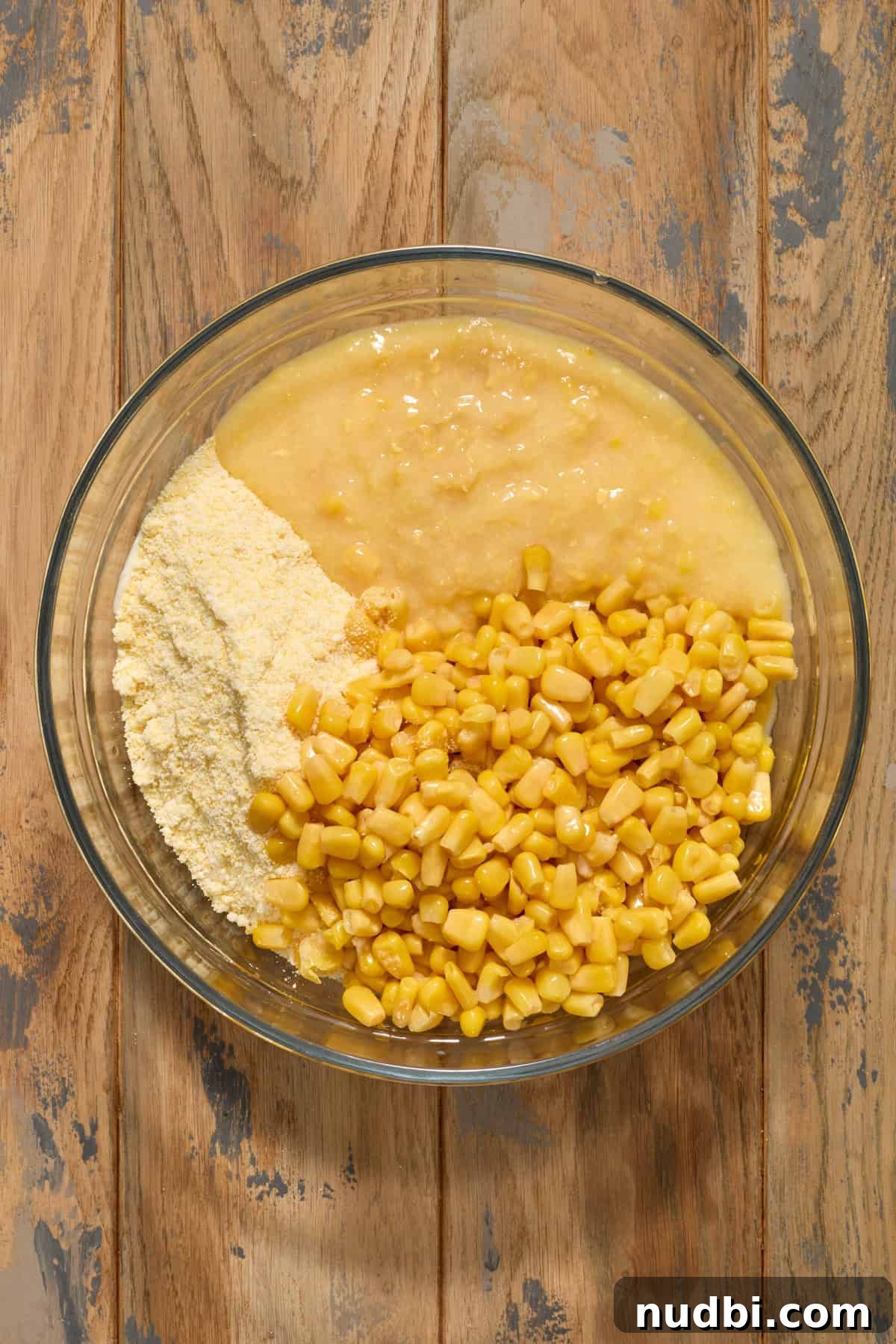 Corn kernels, creamed corn and cornbread mix added to bowl.