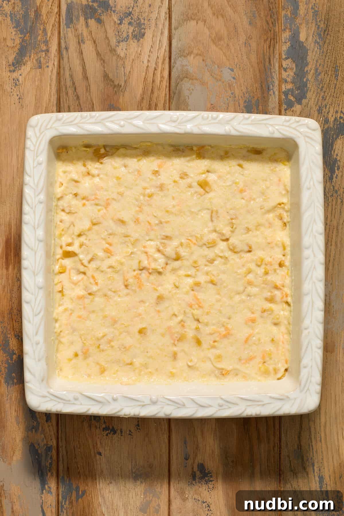 Cheesy cornbread casserole mixture in square pan before baking.