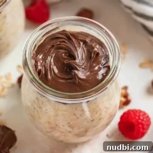 Jar of nutella overnight oats with raspberries beside it.