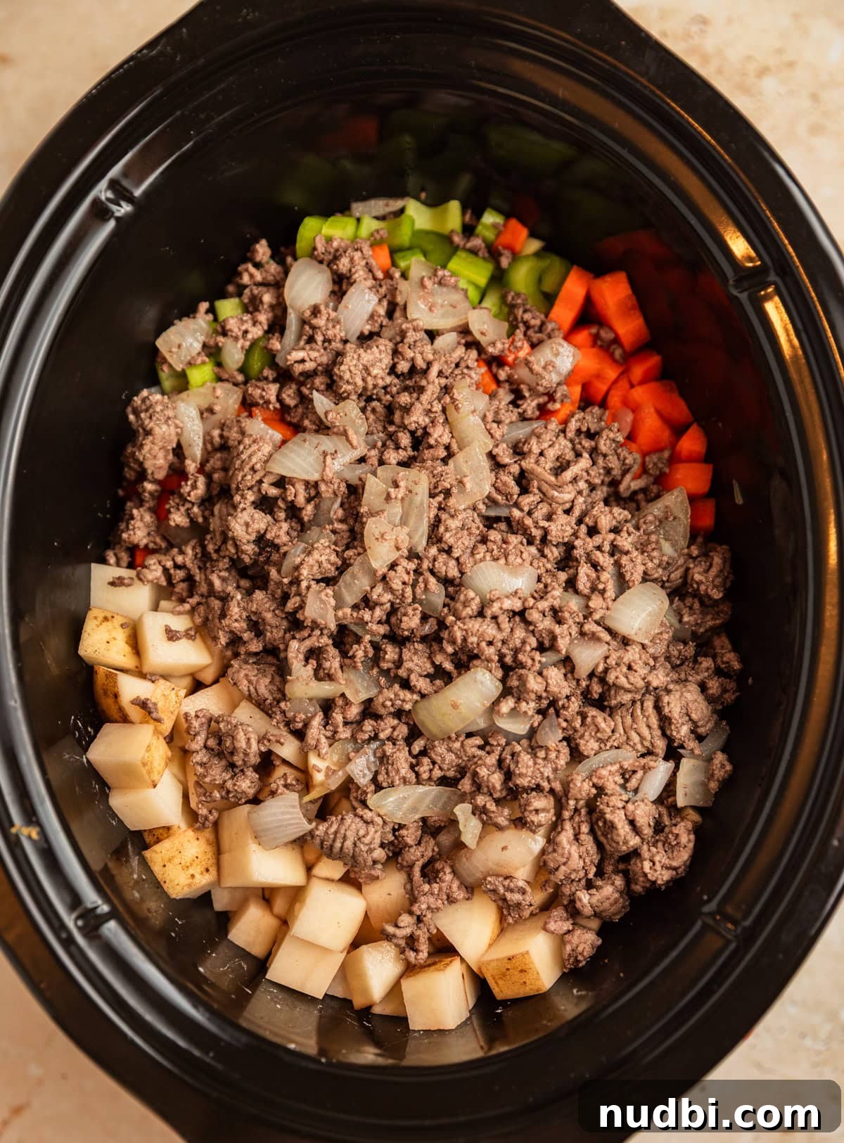 Slow Cooker Cheeseburger Soup Recipe for Weeknight Dinners 6 Beef, potatoes, carrots, and celery in crockpot before cooking.