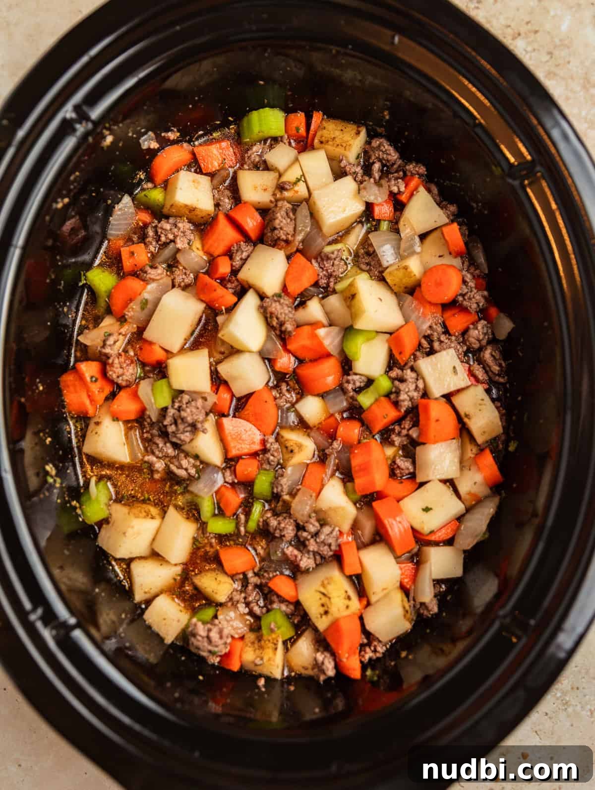 Slow Cooker Cheeseburger Soup Recipe for Weeknight Dinners 7 Meat, vegetables and broth in slow cooker.
