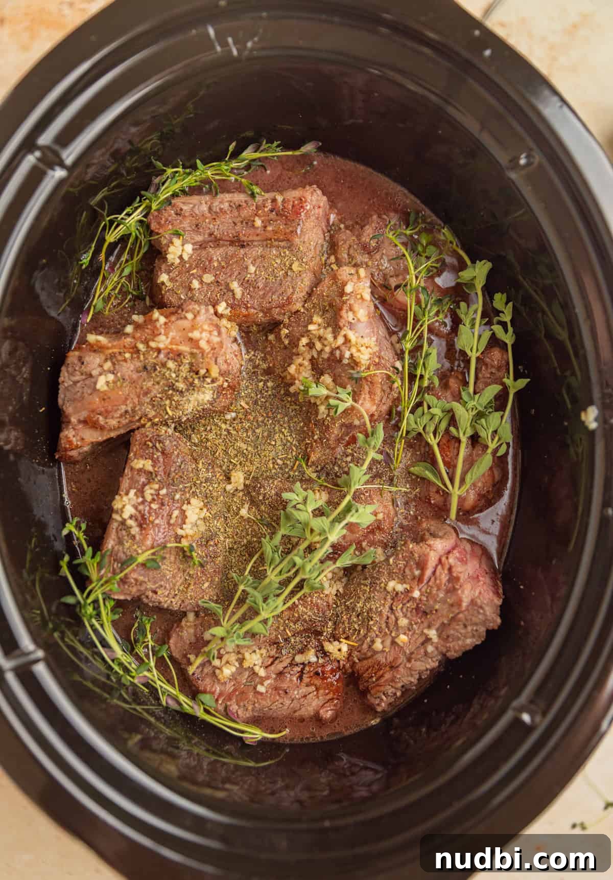 Slow-Cooker Red Wine Braised Short Ribs for Dinner 7 Slow cooker with short ribs, broth and herbs before slow cooking.